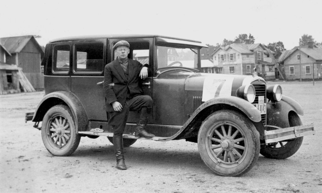 Mustavalkoinen vanha kuva jossa mies nimeltä Valfrid Karvonen seisoo autonsa vieressä torilla.